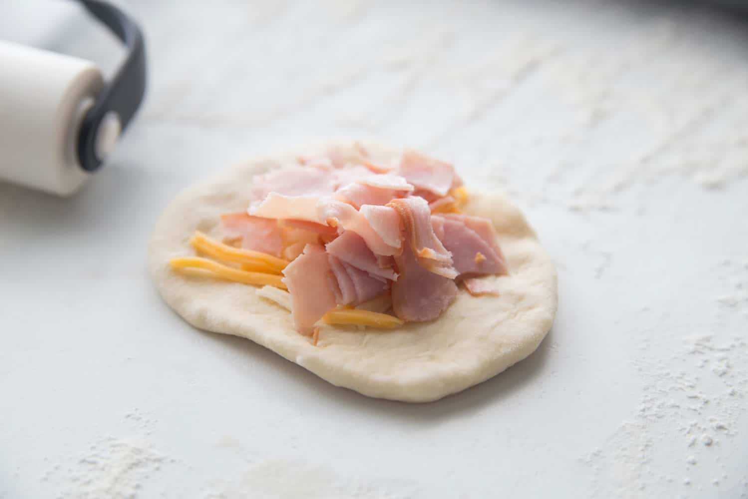 rolled out dough with ham and cheese on top