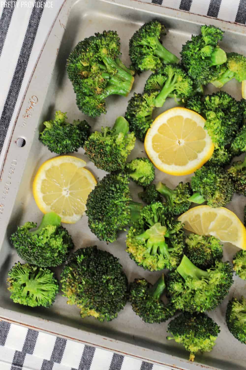 a cookie sheet of roasted broccoli with lemons and seasoning