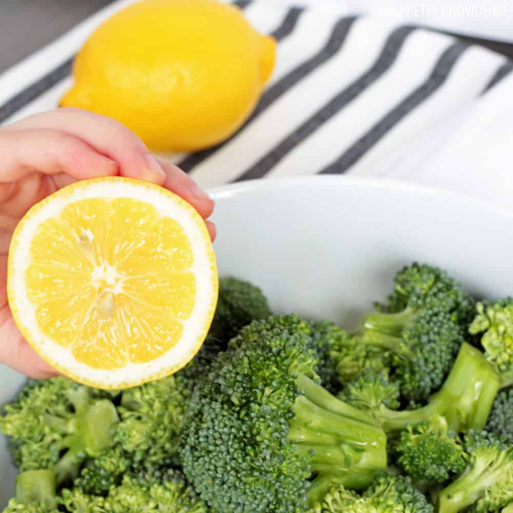 half a lemon about to be squeezed into a bowl of broccoli