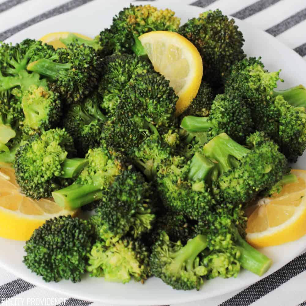 a plate of perfectly seasoned broccoli with lemon wedges 