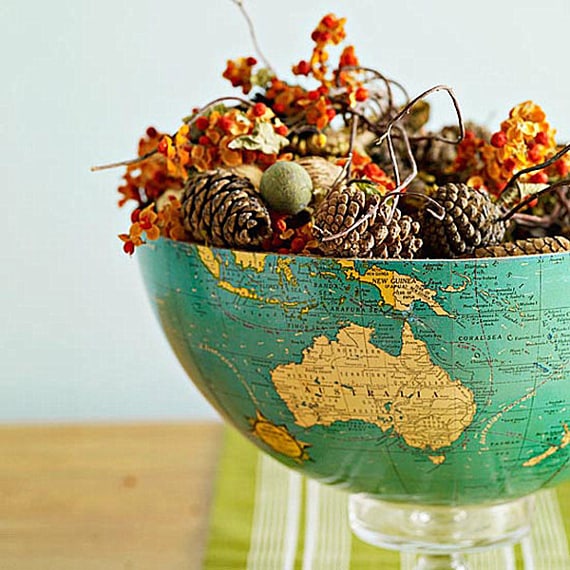 Globe cut in half and used as a bowl with pinecones, fall berries and leaves inside it.