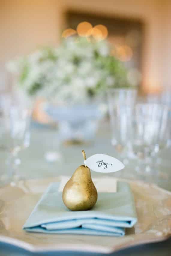 Thanksgiving place setting: gold pear on a blue napkin. A white leaf bearing someone's name in calligraphy on the pear.