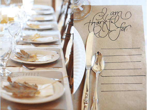 Thanksgiving table setting, with gold leaves on white plates, simple and pretty paper placemat that says 'I am Thankful for'