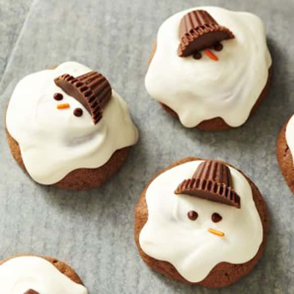 Melted Snowman Cookies wiht Reeses hats and white frosting