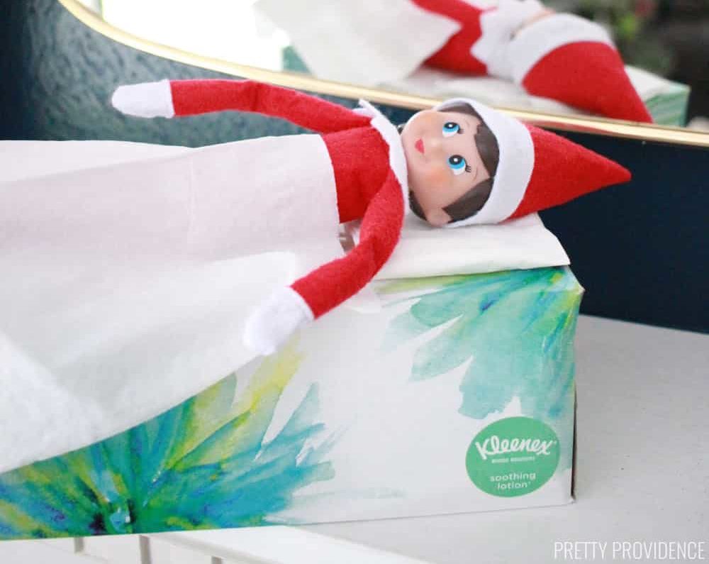 Elf on the Shelf taking a nap on a tissue box 