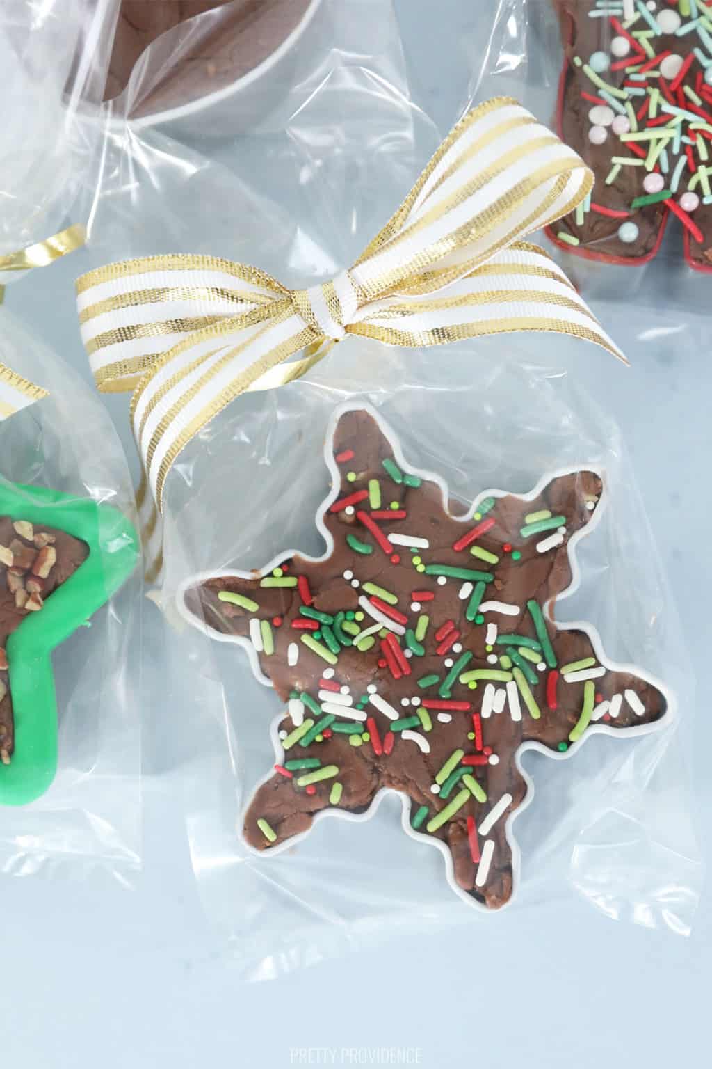 Christmas fudge with sprinkles in a star cookie cutter in clear bags tied with gold ribbon