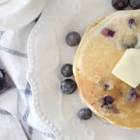 A small stack of blueberry pancakes with a pat of butter on the top.