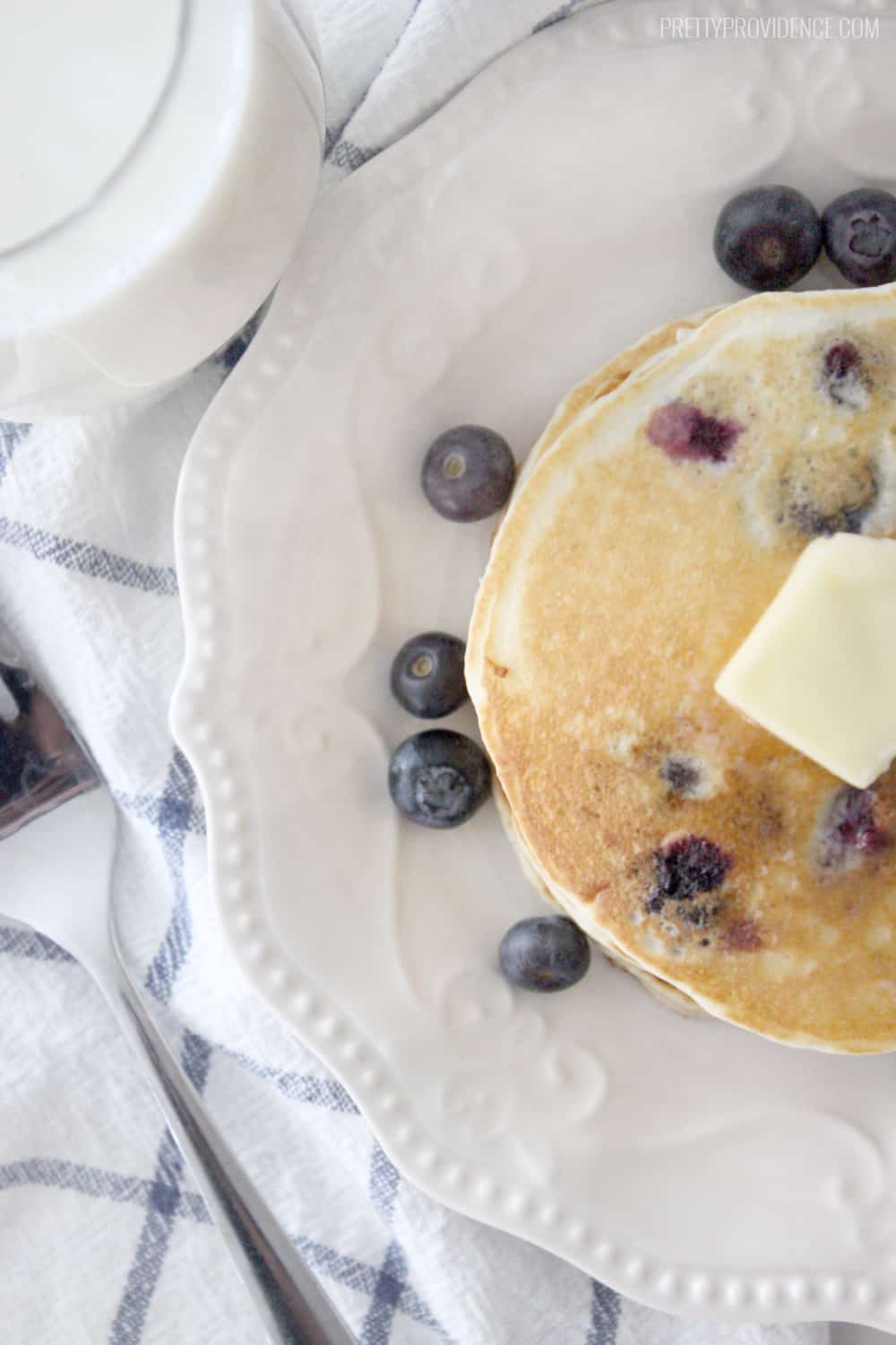 A small stack of blueberry pancakes with a pat of butter on the top.