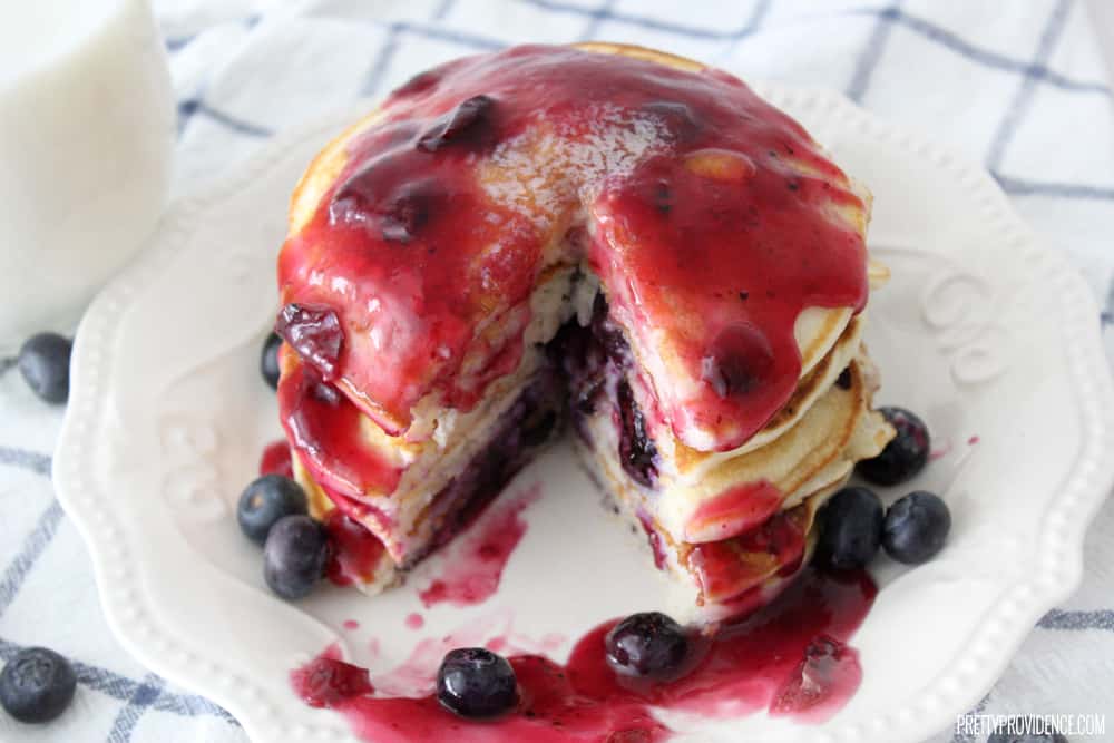 Birds Eye view of a stack of blueberry pancakes on a decorative white plate.