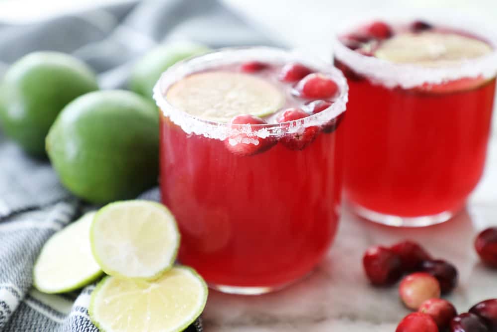 Two glasses of cranberry punch with fresh limes and sugared rims