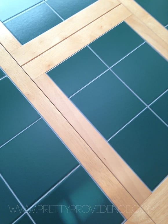 Close up of green tile tabletop with oak trim.