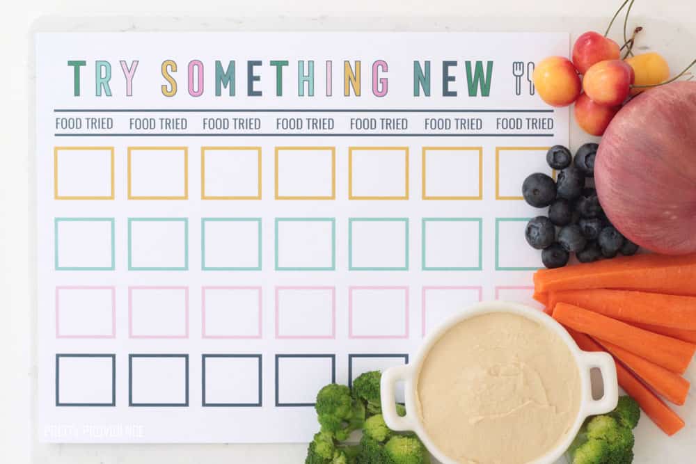 Reward chart for trying new foods with broccoli, hummus, carrots, blueberries, onion and cherries on the side.