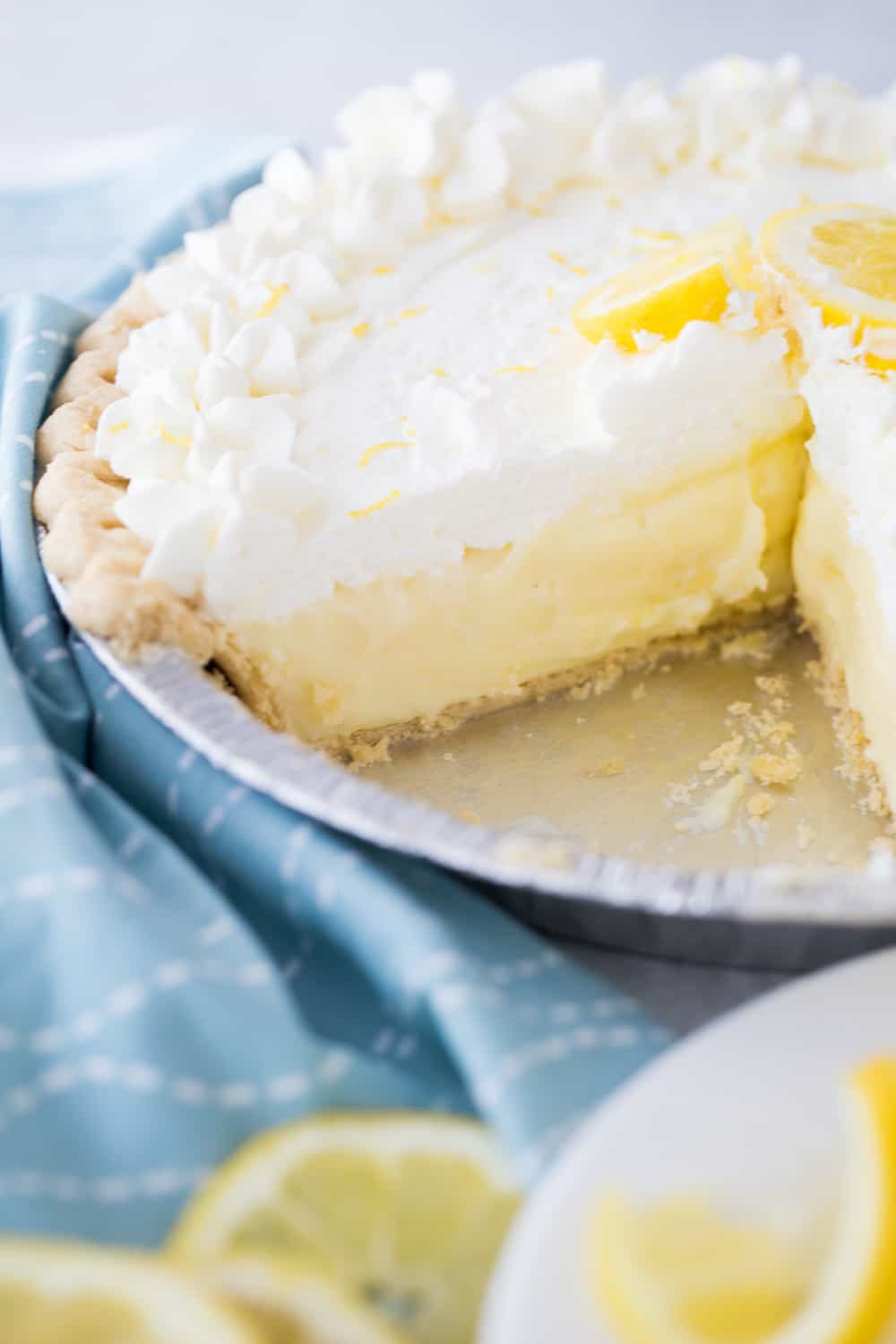 lemon sour cream pie with a slice out of it next to a blue towel