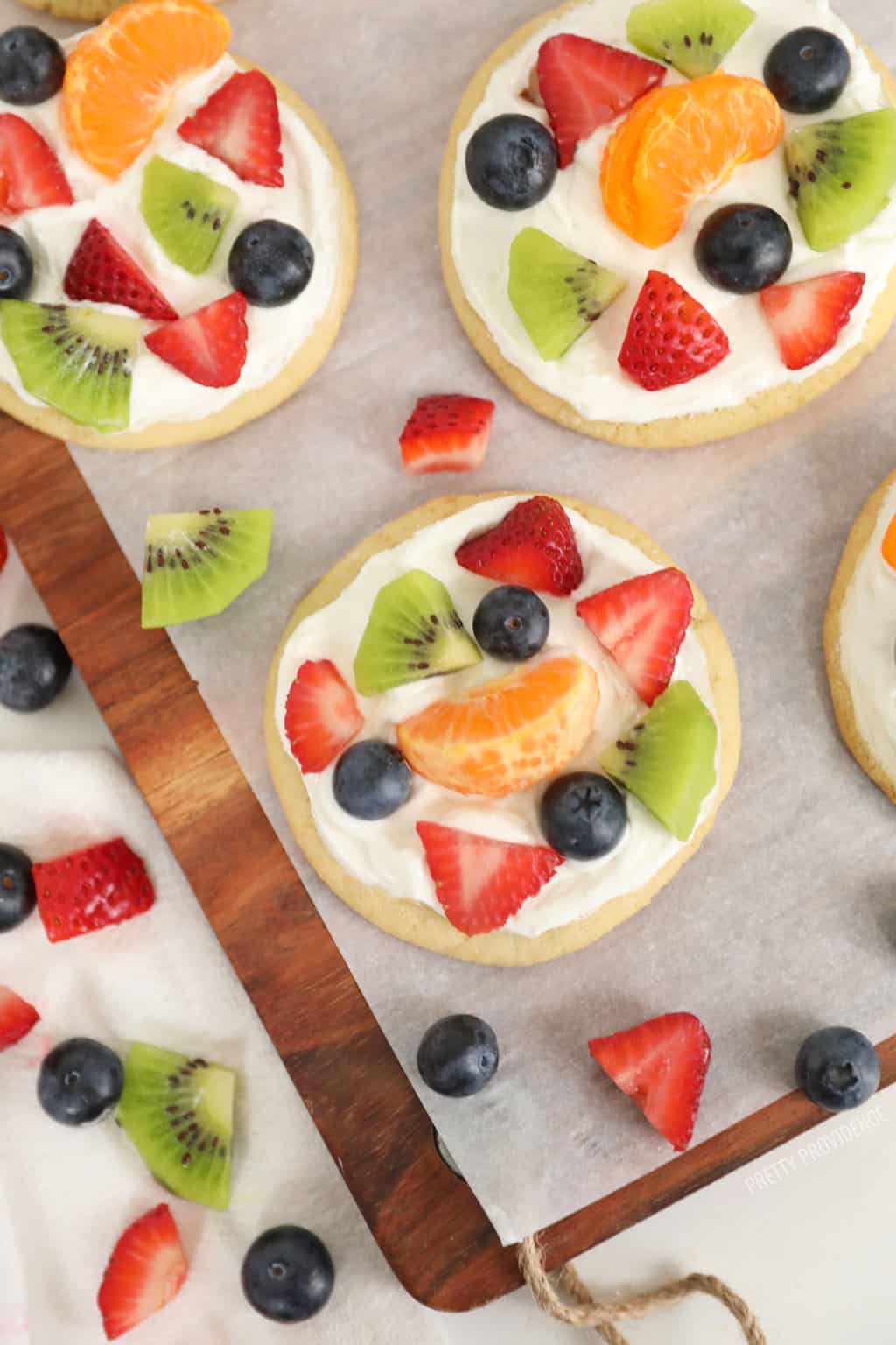 Mini fruit pizzas, strawberries, kiwi, mandarin oranges and blueberries on top of frosted sugar cookies.