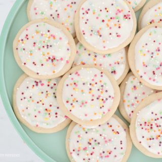 Round sugar cookies with white frosting and colorful sprinkles