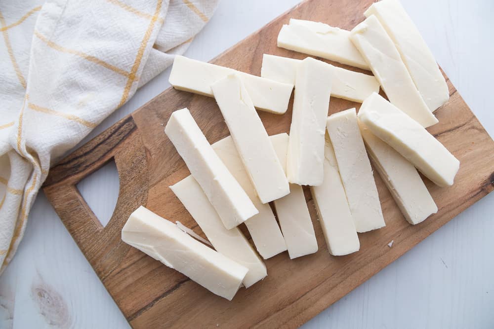 cut sticks of mozzarella lying on a wooden cutting board