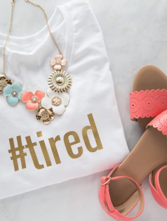white t-shirt with '#tired' written on it in gold iron-on with sandals and a necklace