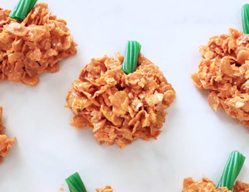 cornflake pumpkins with green licorice stems on a white marble countertop