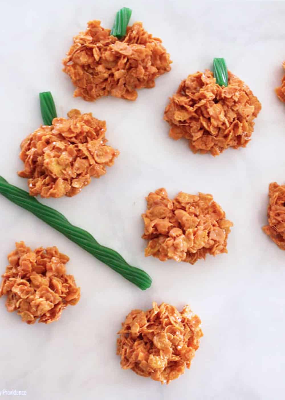 orange cornflake marshmallow treats and green licorice on a white countertop