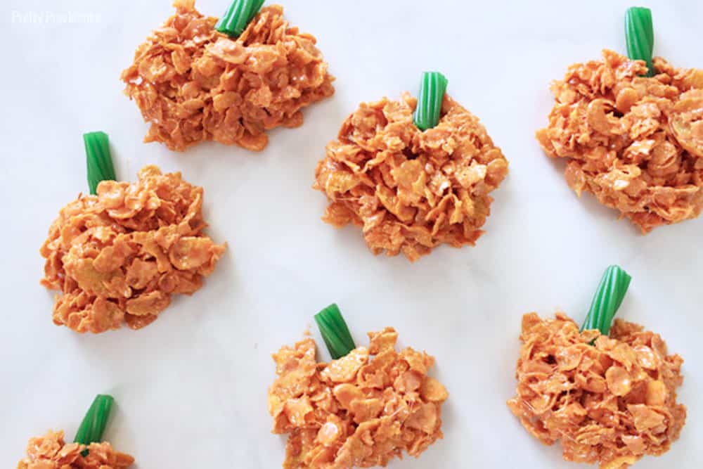 cornflake pumpkins with green licorice stems on a white marble countertop