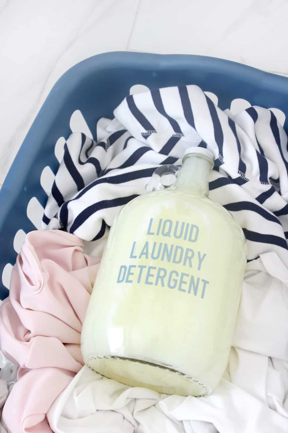 close up of laundry detergent on top of a hamper of dirty clothes