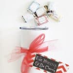 white tumbler with christmas tag on white counter with mini candy bars above it