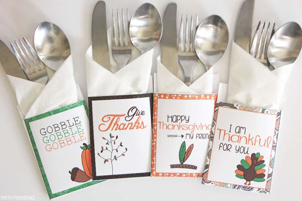 Four sets of silver cutlery wrapped in white napkins and free Thanksgiving cutlery holders.
