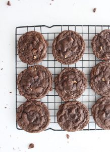 Double chocolate chip cookies lined up on a cooling rack on a white countertop