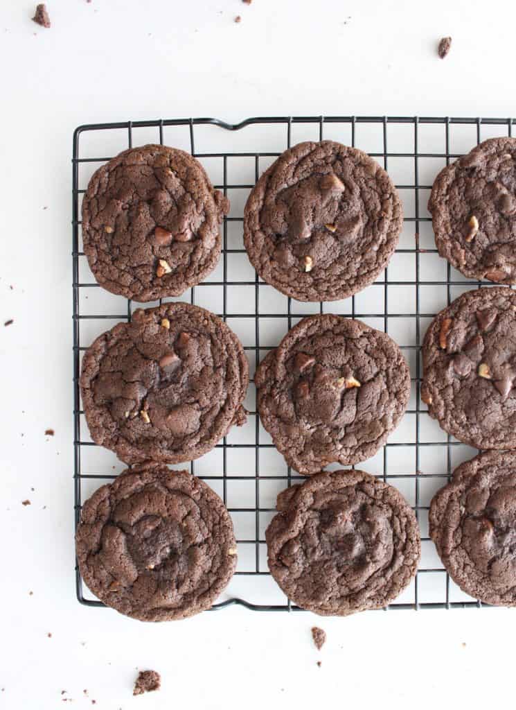 Double chocolate chip cookies lined up on a cooling rack on a white countertop