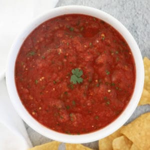 Bird's eye view of a small bowl of restaurant style salsa next to tortilla chips.