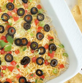 Seven layer bean dip in a white dish with chips