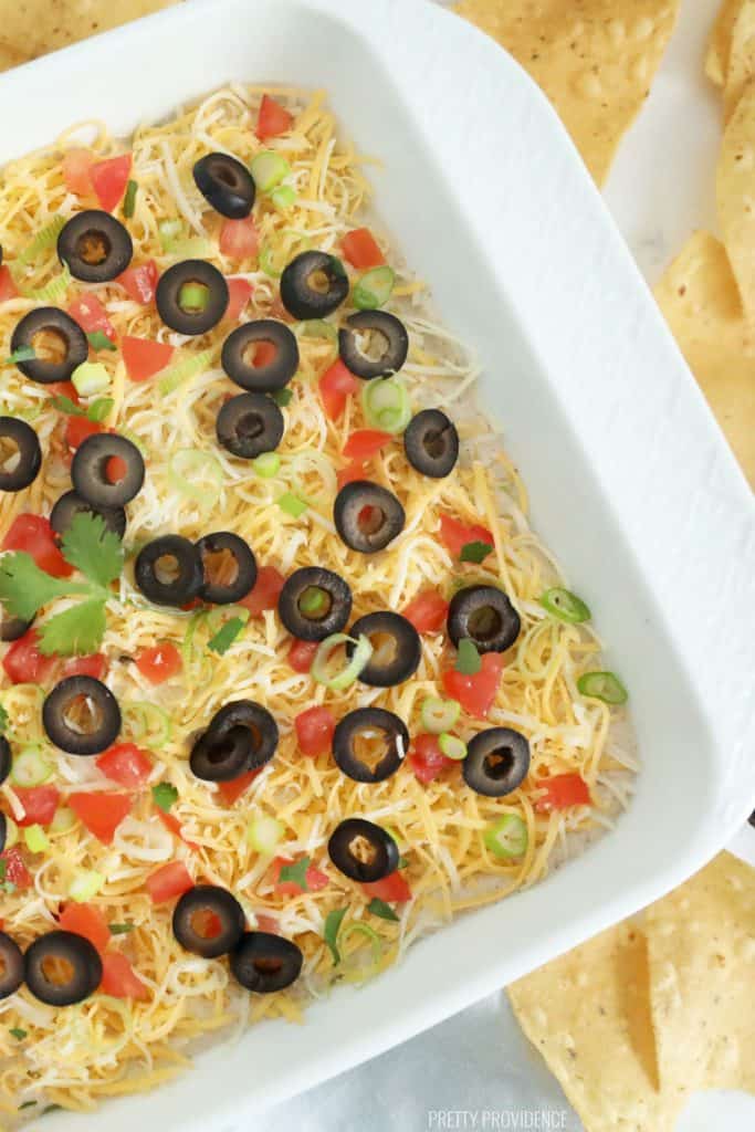 Seven layer bean dip in a white dish with chips