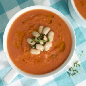 Tomato and White bean soup in a rustic bowl with thyme and white beans on top as a garnish.