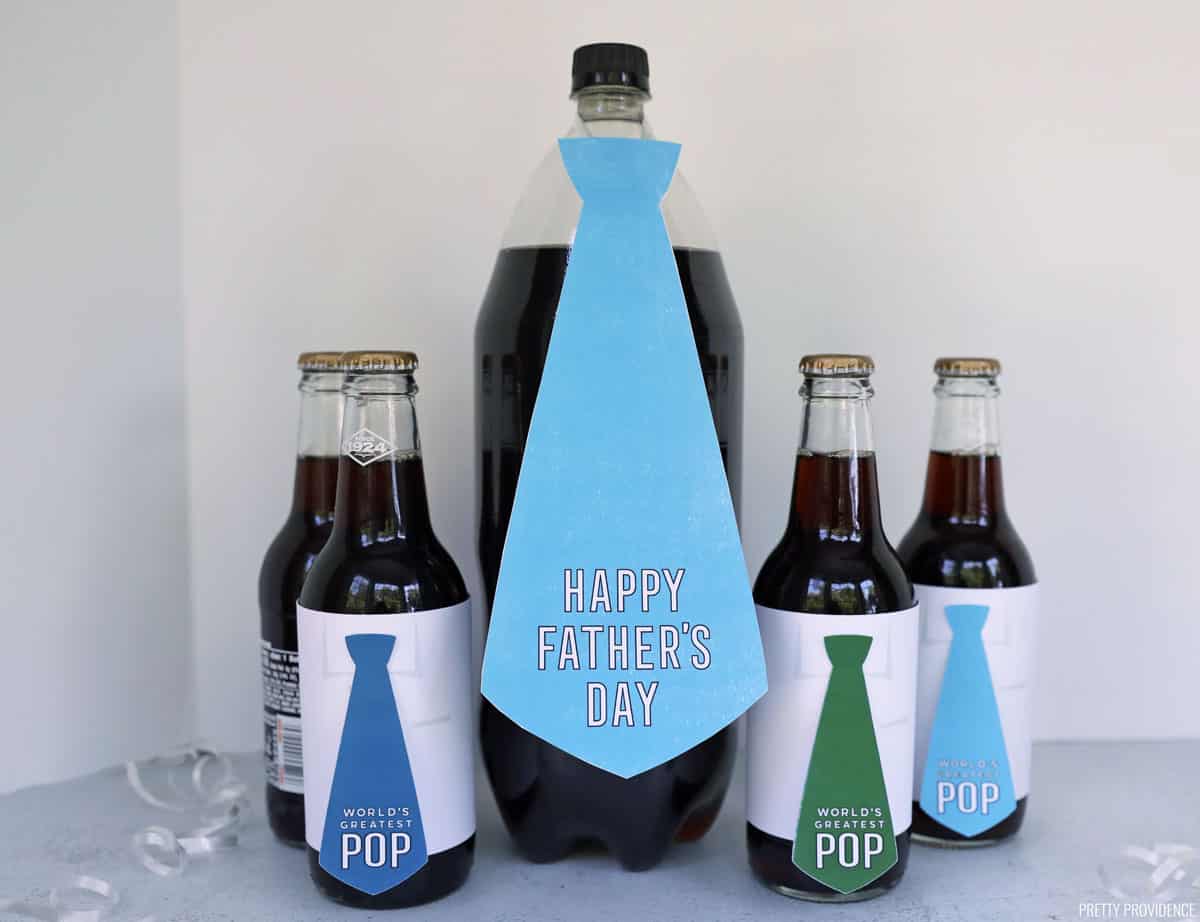 Father's day printable gift tags in the shape of neckties that say 'happy father's day' and 'world's greatest pop' taped onto root beer bottles