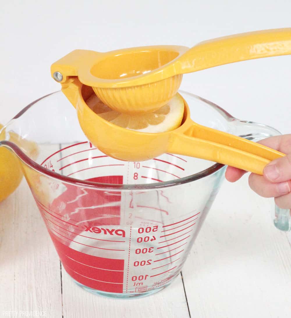 Citrus squeezer with half a lemon inside it, over a measuring cup. Squeezing lemons for lemonade.