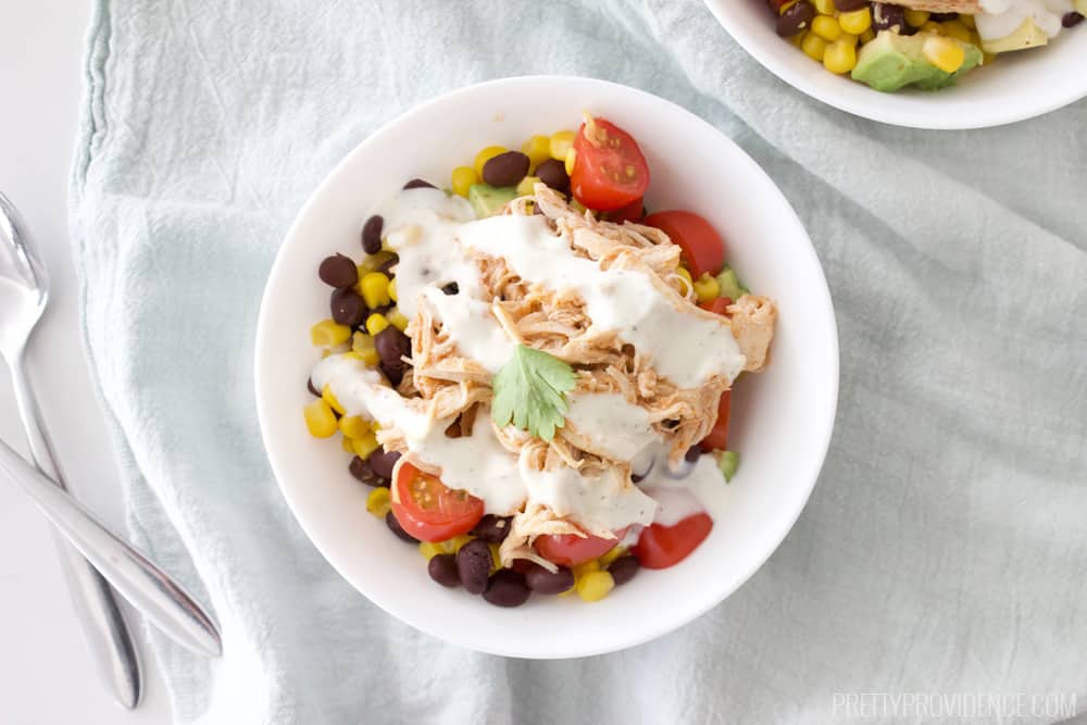 a white bowl filled with healthy ingredients on a pale blue tea towel next to crossed silverware