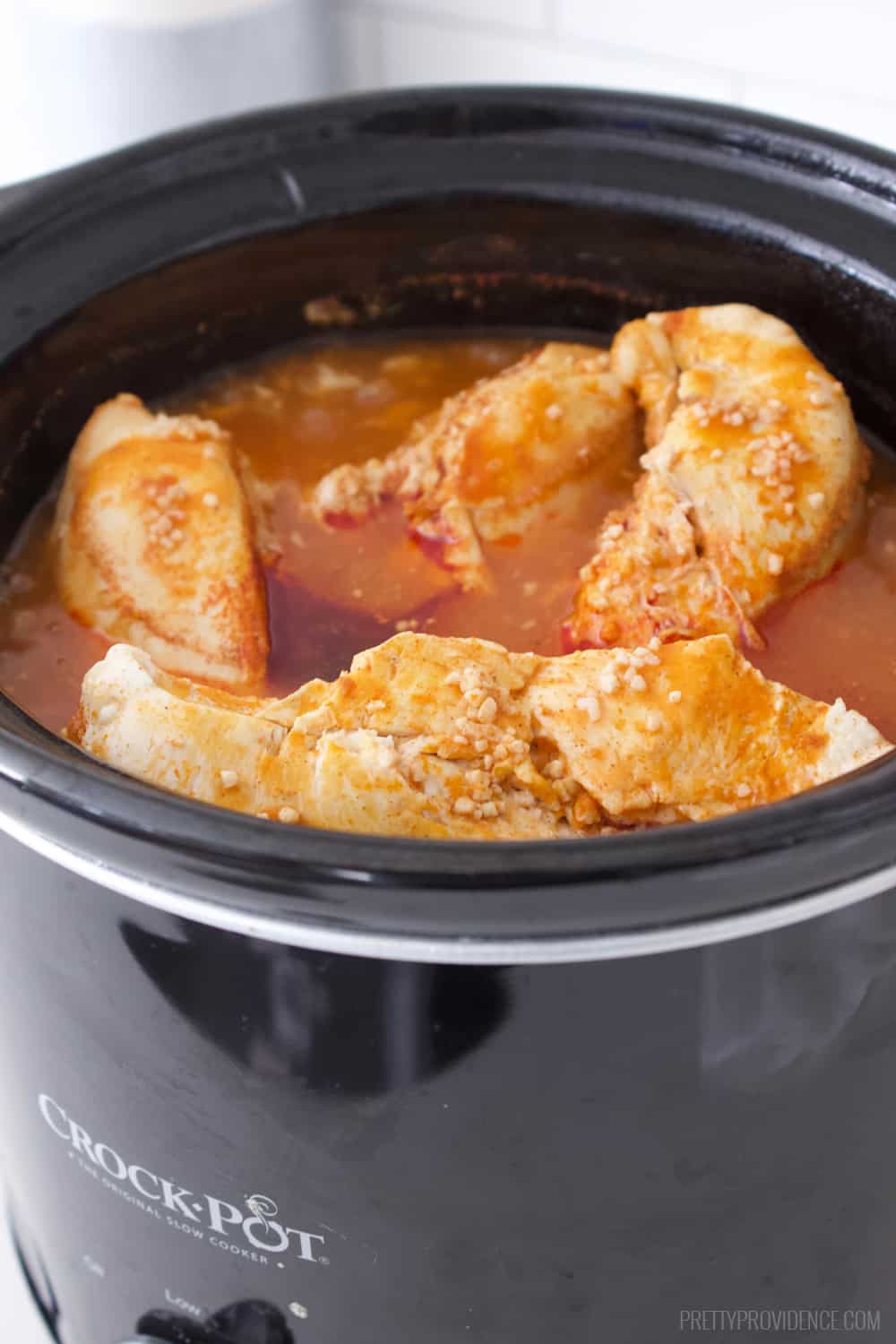 Buffalo chicken cooking in crock pot. 