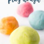 Homemade playdough recipe, yellow, orange, blue and pink dough on a white surface.