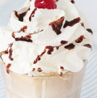 Root Beer Float in a glass, topped with whipped cream, chocolate syrup and a maraschino cherry.