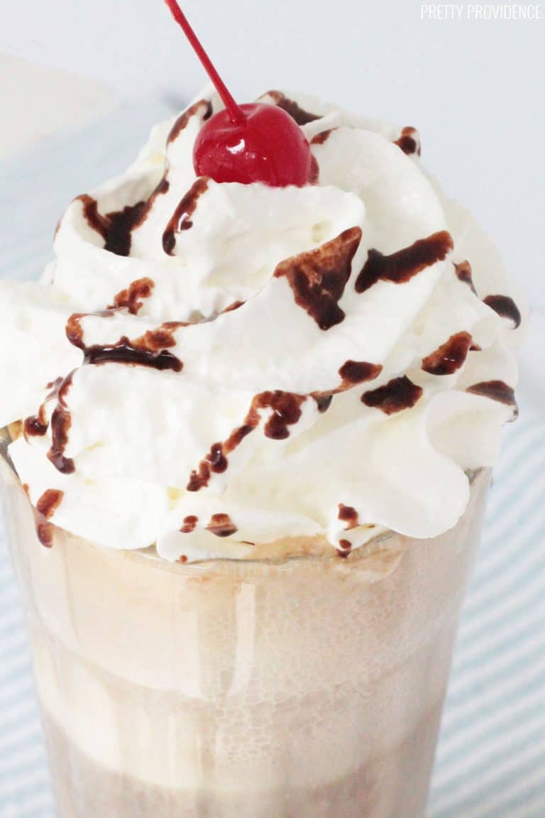 Root Beer Float in a glass, topped with whipped cream, chocolate syrup and a maraschino cherry.