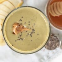 Healthy Chocolate Peanut Butter Smoothie with a dollop of peanut butter and chia seeds on top, honey, chia seeds and banana on the side.