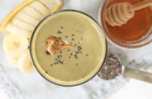 Healthy Chocolate Peanut Butter Smoothie with a dollop of peanut butter and chia seeds on top, honey, chia seeds and banana on the side.