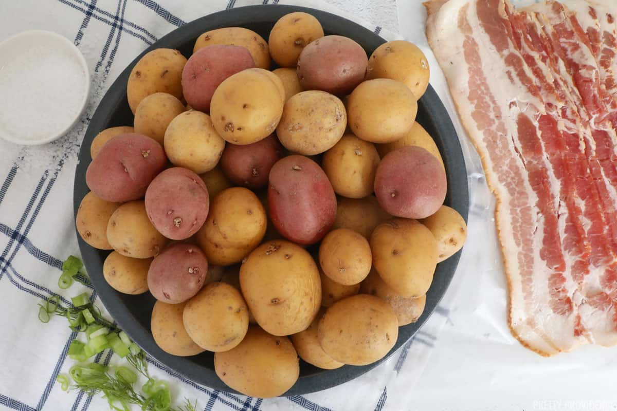 New potatoes in a white bowl, bacon on a white plate and mayonnaise in a small prep bowl.