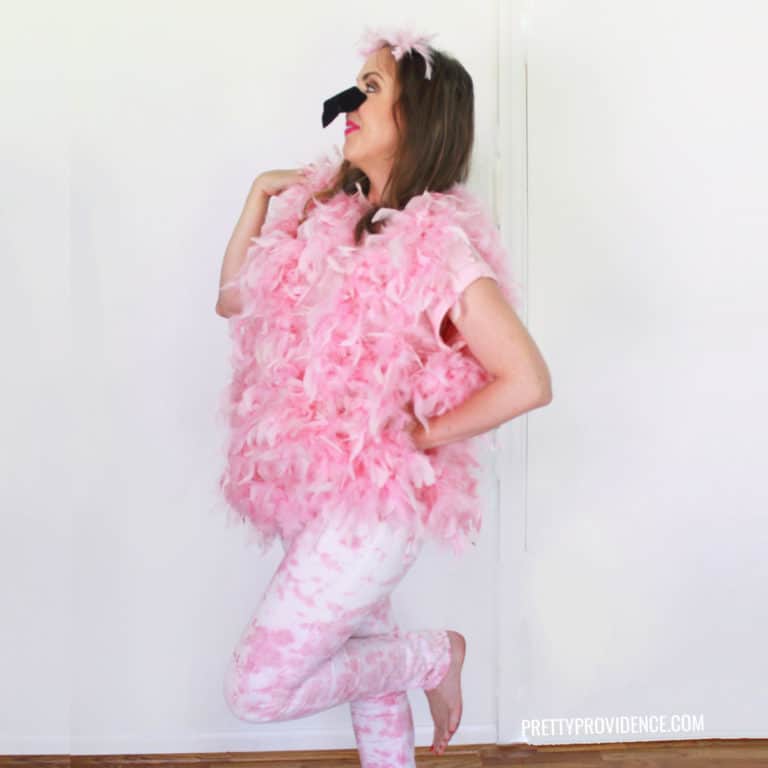Woman wearing a DIY Flamingo costume, wearing pink and white tie-dye pants, pink feather boas and a black felt nose.