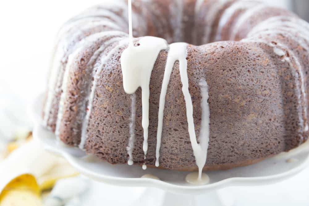 Glaze being poured onto a bundt shaped banana cake.