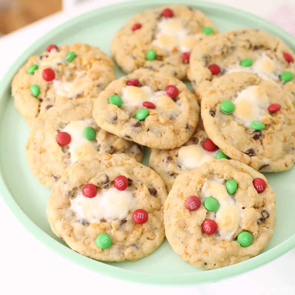 Cookies with red and green mini m&m's, cornflakes and melted marshmallow on a green plate