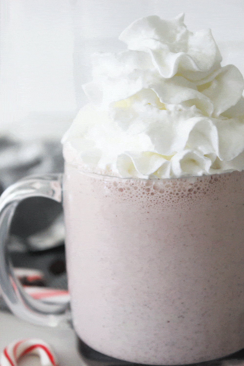 close up of peppermint milkshake topped with whipped cream in a clear mug