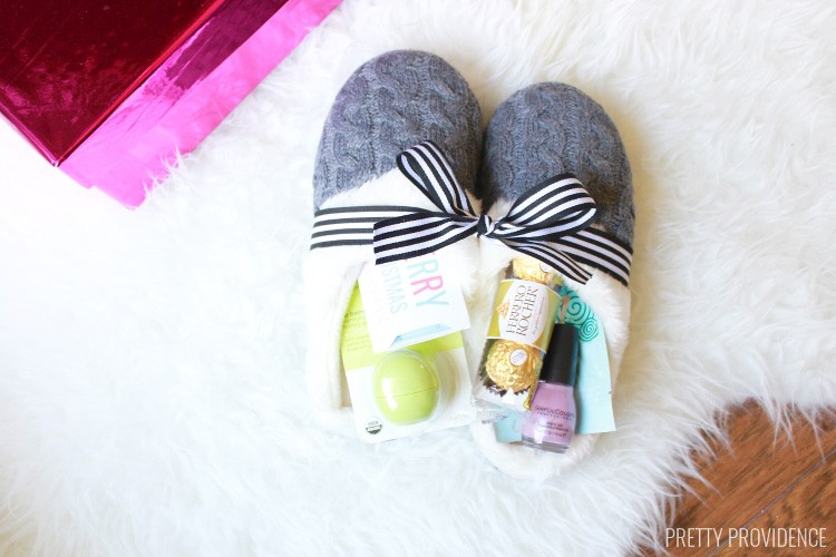 grey slippers filled with small gifts and treats on a white faux fur rug
