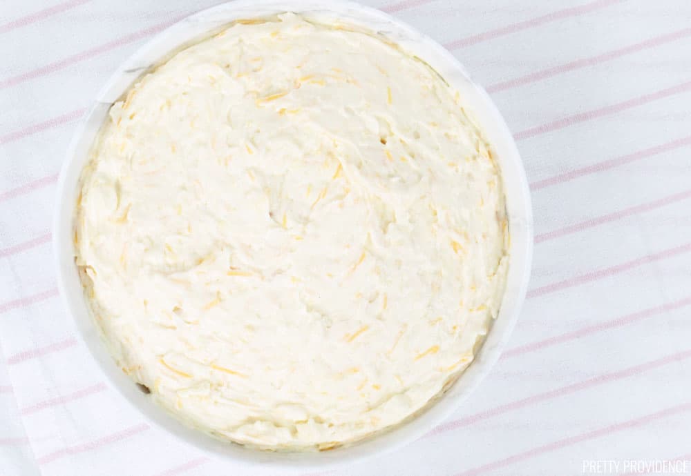 Cheesy potato casserole sour cream and cheese mixture in a white bowl.
