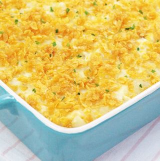 Potato Casserole AKA Funeral Potatoes in a blue 9x13 baking dish topped with cornflakes and chives.